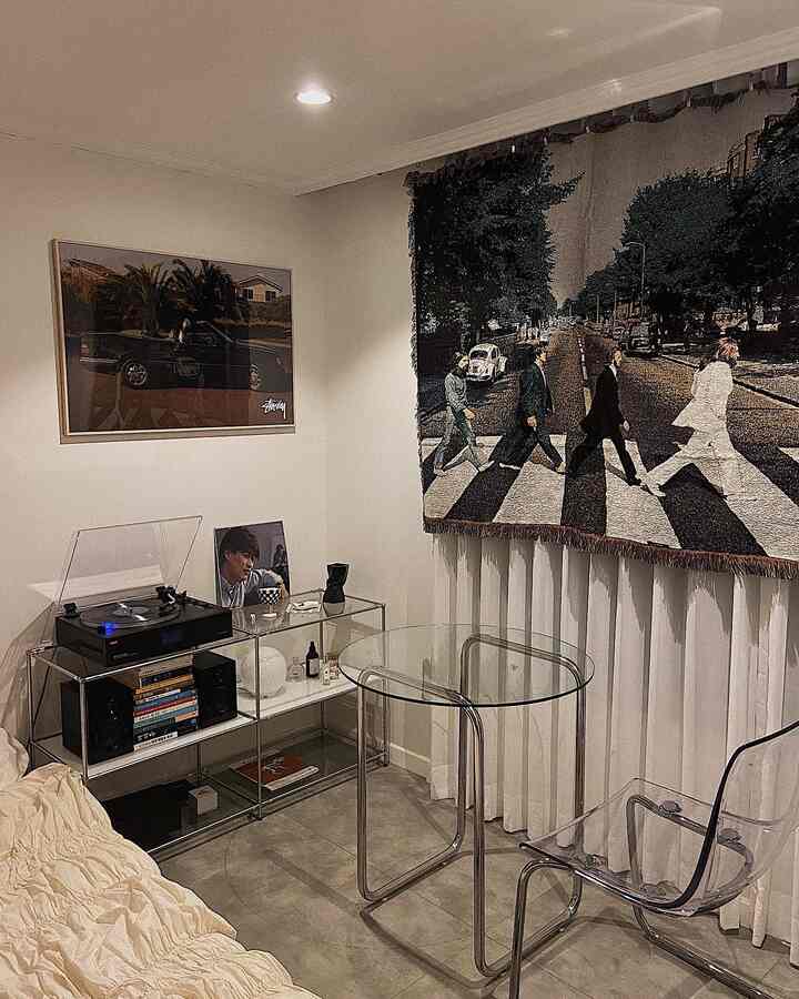 A modern bedroom with white curtains as background, featuring transparent chairs, glass table, modular furniture and posters in a cozy setting
