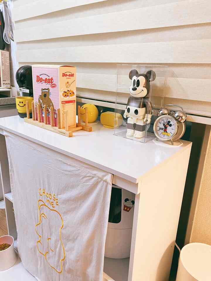 ベージュのブラインドと白い家具が調和した空間、ミニコーヒーマシンとペット用品のある居心地の良いおうちカフェ風インテリア