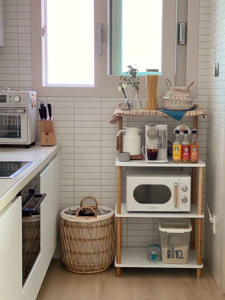 Compact kitchen space in white and wood tones featuring a coffee machine and microwave with a natural home cafe vibe
