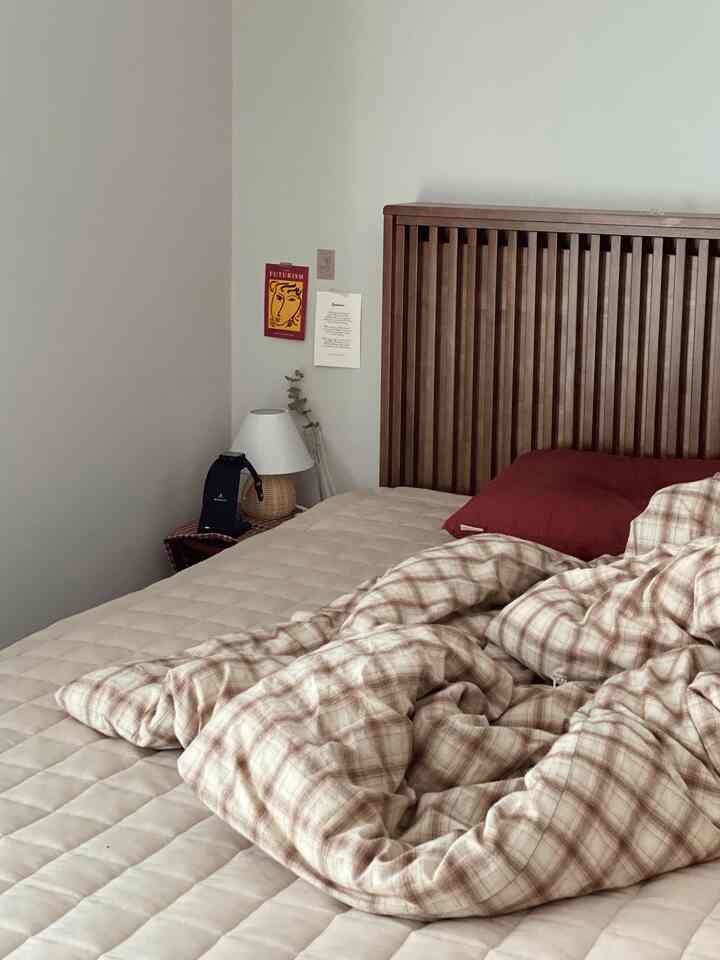 Beige and brown bedroom featuring a dark wooden bed, checkered duvet, and pillow with a natural, cozy feel
