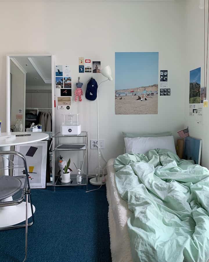 ブルーのカーペットとミント色の寝具が調和した一人暮らしの寝室、シンプルでミッドセンチュリーモダンな印象的なインテリア