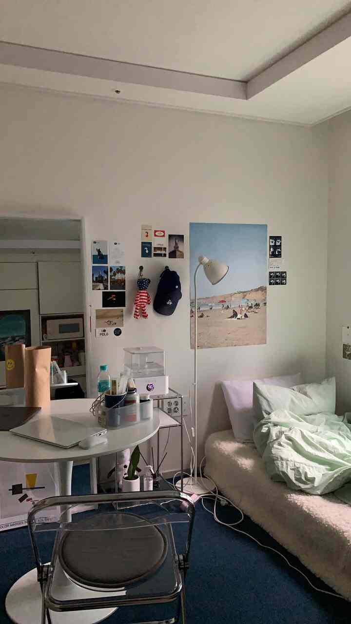 A compact single household bedroom with white walls and blue carpet, featuring a small round table and a bed for a cozy atmosphere