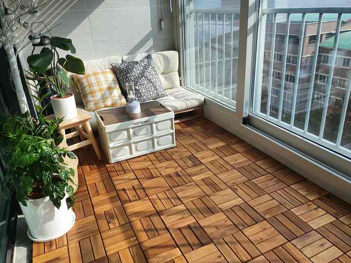 Cozy veranda with warm wood tone flooring, comfortable sofa, and greenery arranged for natural atmosphere