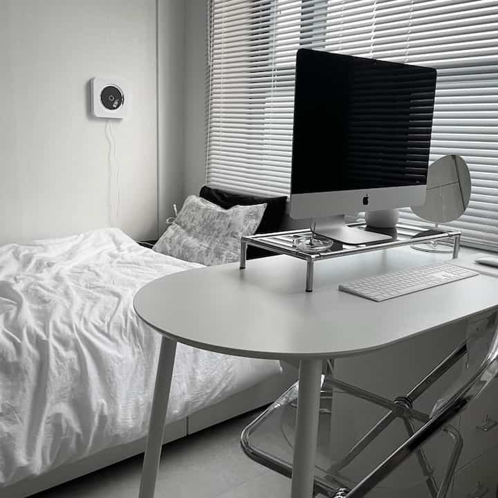 白を基調とした寝室兼ホームオフィス、白いベッドとデスクにiMacが配置された雰囲気のあるモダンな空間