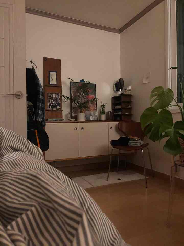 Natural bedroom space featuring wood tones and white colors, with a sideboard and plants creating a cozy atmosphere.