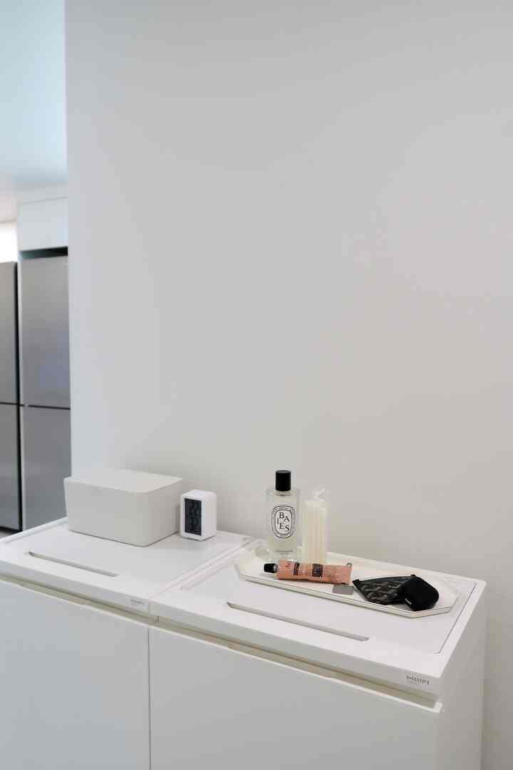 White-toned entrance space featuring functional recycling bins with storage trays and a clean, modern interior