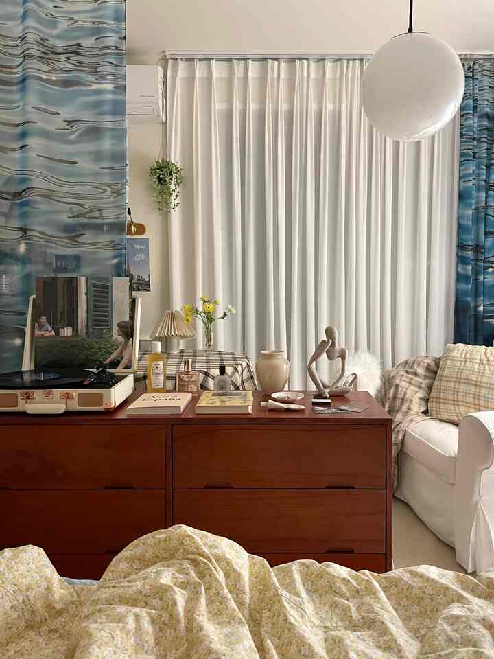 白と茶色の色調のリビング、中央に大きなチェストと白いアームチェアが配置され、ヴィンテージな雰囲気のある印象的な空間