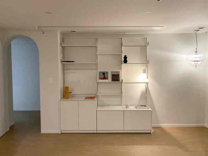 Minimal study extension space with white and wood tones featuring an arch door and System000 shelving
