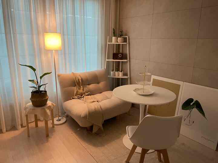 Cozy living room with warm beige and white tones featuring an ivory sofa, round dining table, and floor lamp