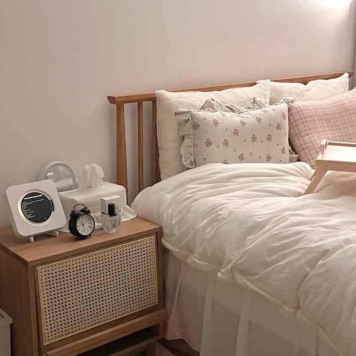 Cozy bedroom with natural wood tone bed frame and white bedding elements