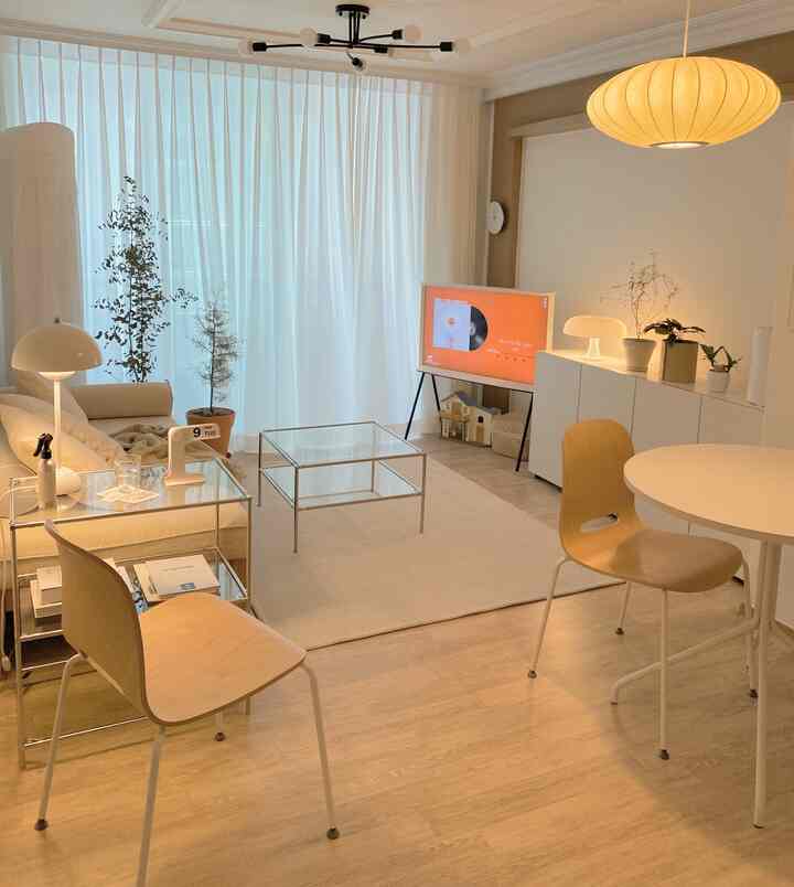 Small living room in white and wood tones featuring steel furniture and glass tables with a modern and simple atmosphere