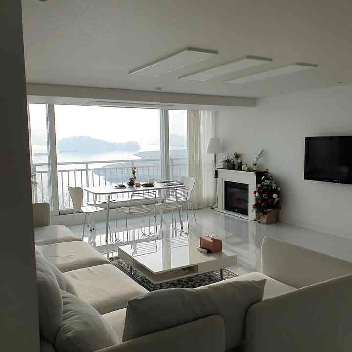 White-toned living room with IKEA sofa and white dining table, modern space featuring ocean view