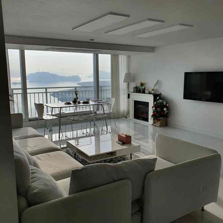 White toned living room featuring large sectional sofa and dining set with minimal and natural ambiance