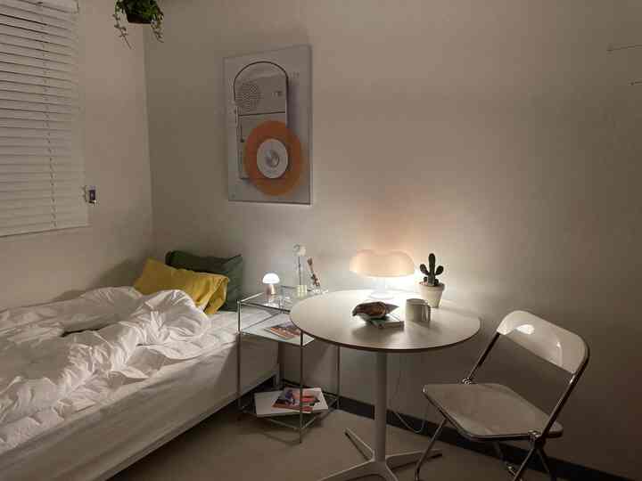 White-toned single household bedroom featuring a round table with lamps, creating a cozy atmosphere