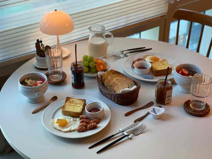 白い円形テーブルとナチュラルな小物が配置されたダイニング、ホームブランチの準備が整った雰囲気のあるおうちカフェ空間