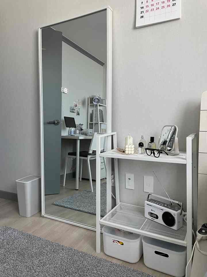 Minimal white-toned small room featuring a large full-length mirror and tidy shelving unit in an Instagrammable style
