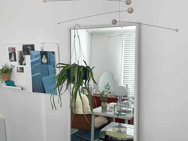 White and green toned home office featuring hanging plants and mobiles with a minimal and airy interior