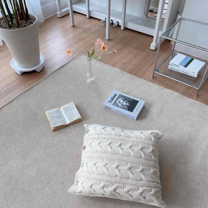ベージュ調のリビング空間、ニットクッションとラグが温かみのあるナチュラルな雰囲気を演出するインテリア