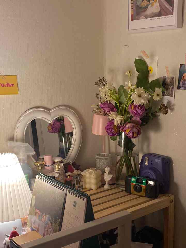 Natural color small room featuring wooden table with vase, candles and pink table lamp creating cozy atmosphere