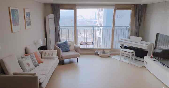 Bright and cozy living room with a white and natural color palette, featuring sofa and piano