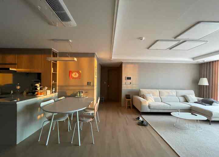 ベージュとアイボリーの色調のリビングとキッチン、モダンでシンプルな家具が配置された温かみのある新婚宅のインテリア