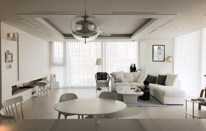 Bright white and wood-toned spacious living room with large sofa and a child playing peacefully, family-oriented 40-pyeong residence