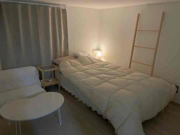 ベージュとナチュラルウッドのトーンが調和した、ベッドとソファが配置された雰囲気のあるロフト風寝室