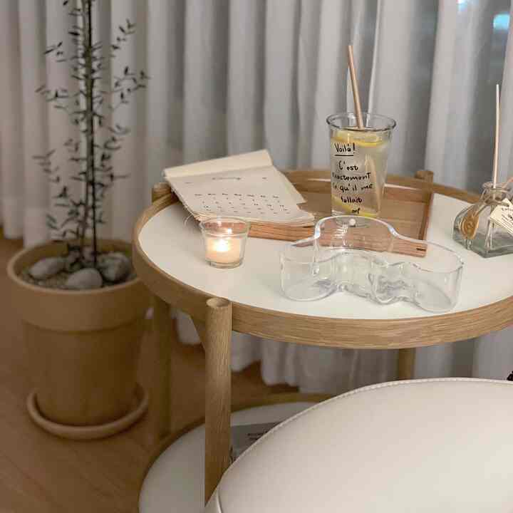 Cozy home cafe space with a wood tone and white side table featuring a tray, glass, and candle