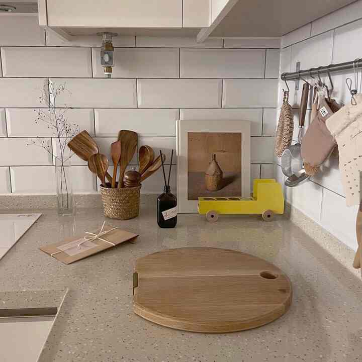 白いタイル壁と茶色の木製調理器具が配置されたナチュラルな雰囲気のキッチン空間