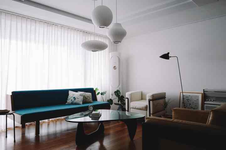 A white and blue toned Mid-Century Modern living room featuring sofas and a glass coffee table with a clean layout
