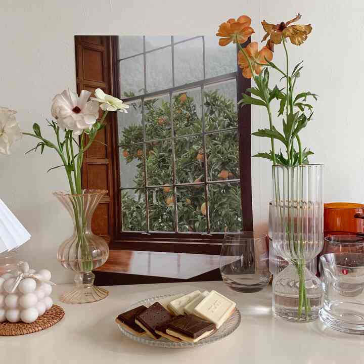 Bright space with white walls and brown wooden window frame, featuring transparent glass vases and home cafe items, creating a clean natural atmosphere