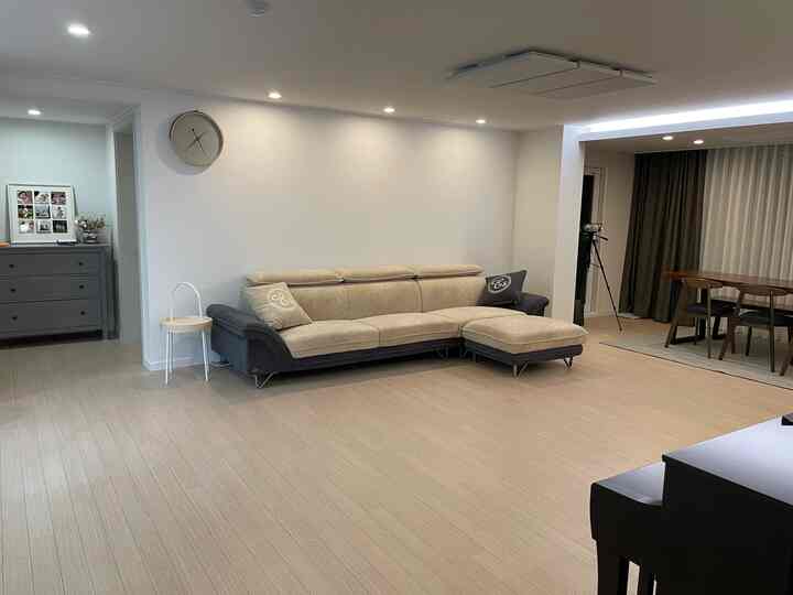Bright white-walled living room featuring beige and dark gray sectional sofa with open layout