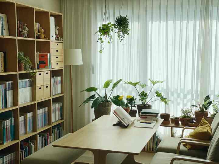 Natural-toned cozy study featuring white curtains and wooden bookshelves