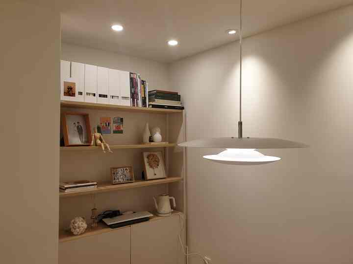 White and natural wood tone dining room featuring pendant light and neat storage shelves in a simple setting