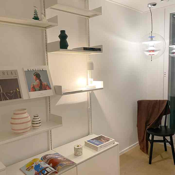 Compact study space with white walls and wood-tone flooring, featuring pendant light and candle warmer creating a warm atmosphere