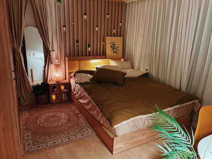 Cozy bedroom with beige and wood tones, featuring a wooden bed, nightstand, curtains, and rug creating a warm atmosphere