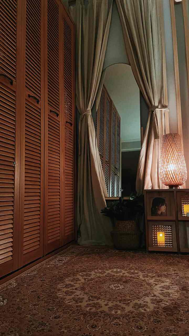 Cozy corridor space featuring warm brown and beige closet, curtains, rug, and a woven floor lamp