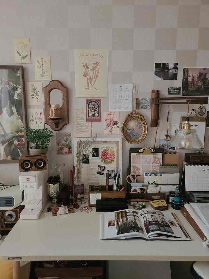 White and wood tone studio desk space featuring vintage decor and wall art, creating a cozy atmosphere