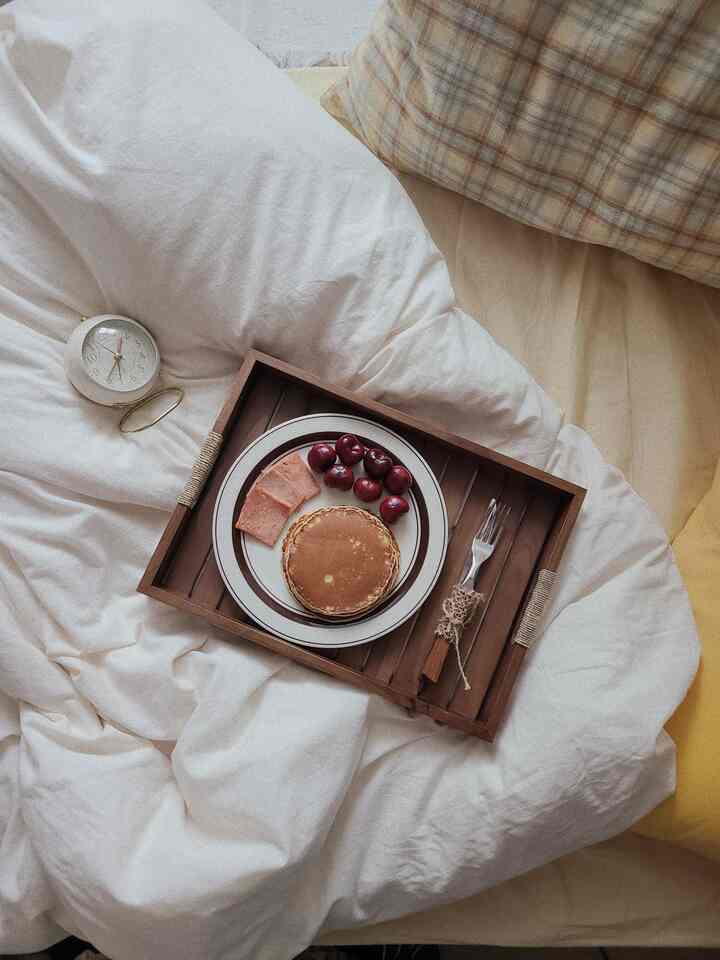 White and brown toned bedroom featuring a bed with wooden tray and brunch, creating a cozy atmosphere