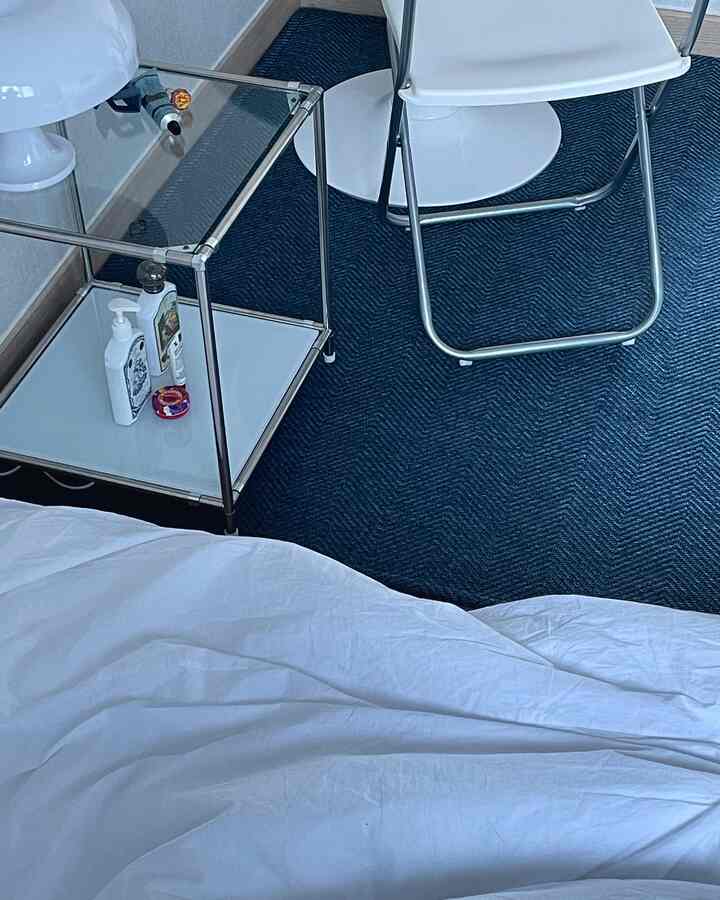 White and navy toned bedroom featuring a white folding chair and chrome side table in a calm setting