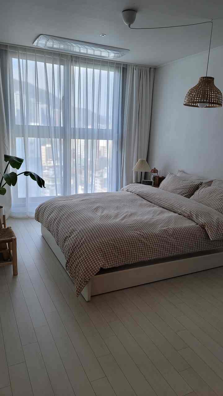 白とナチュラルの色調が調和した6畳寝室、チェック柄寝具とラタン照明が配置されたシンプルモダンなインテリア