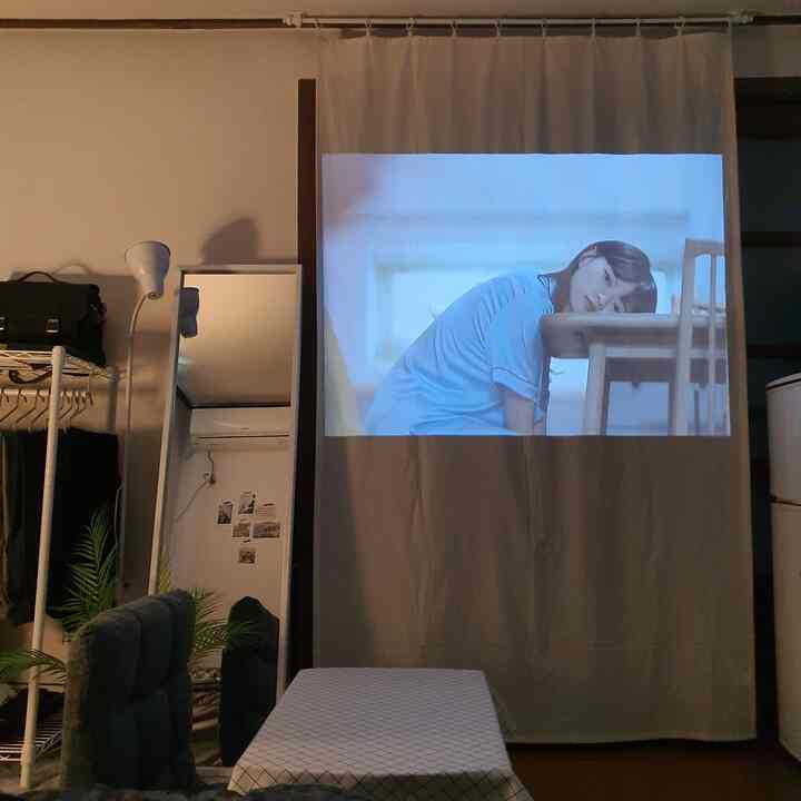Natural-toned small kitchen space with a partition curtain used as a projector screen, showcasing practical interior design
