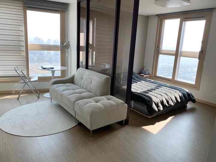 Natural wood-toned studio apartment living and bedroom space featuring modern furniture with a cozy atmosphere