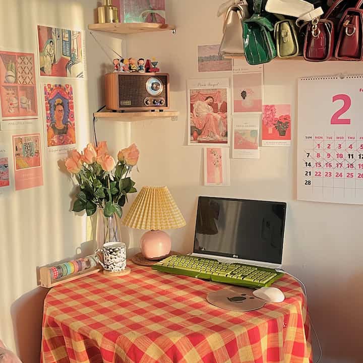 Home cafe space in pink and red tones featuring retro radio, table lamp, calendar and various wall decor creating a cozy atmosphere