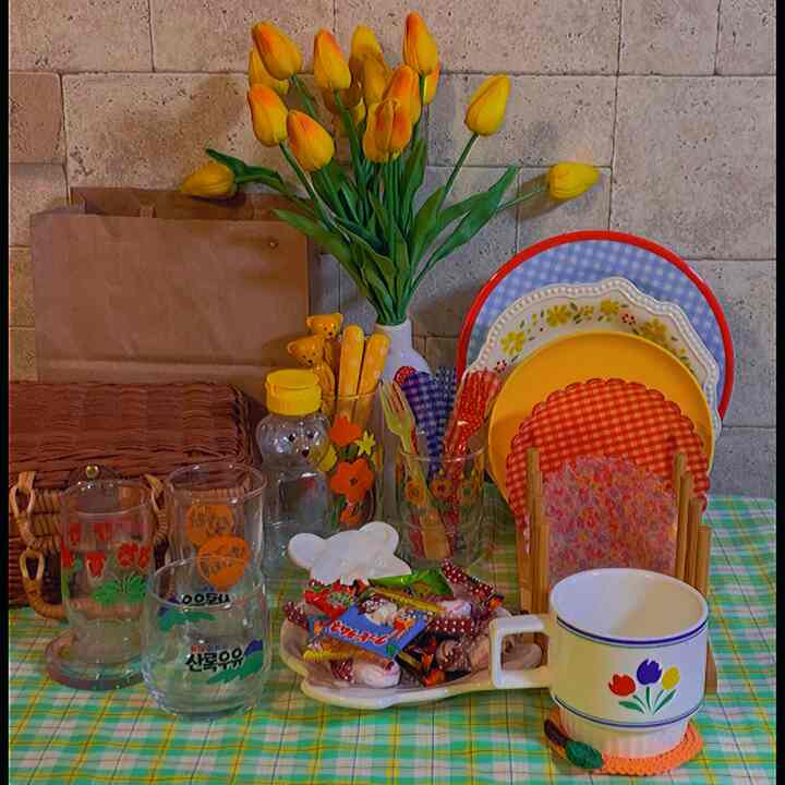 黄色いチューリップの花瓶とヴィンテージの皿やカップ、小物が配置された雰囲気のあるおうちカフェ