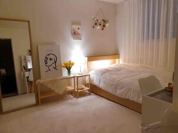 白と木目調が調和した寝室、ベッドとナイトテーブル、テーブルランプが配置された雰囲気のあるインテリア