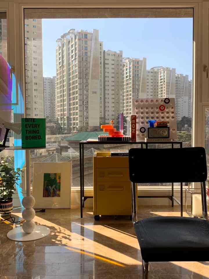 Bright natural-light filled natural modern home office featuring black chair and yellow storage cabinet