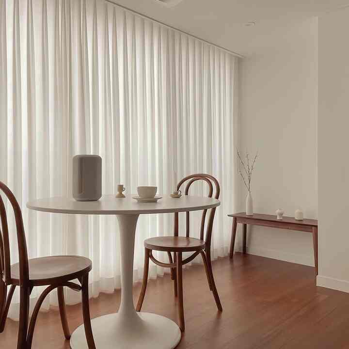 Ivory and wood tone living room featuring a round dining table and wooden chairs creating a cozy, natural atmosphere