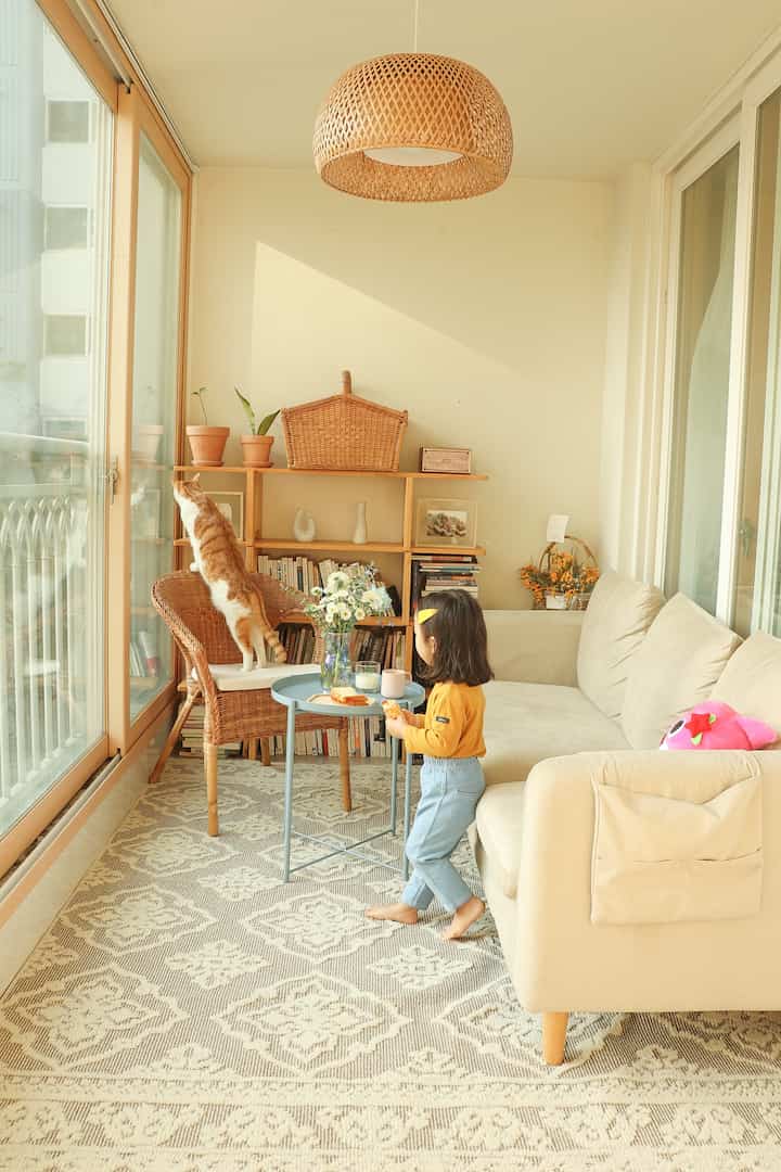 Beige and wood tone living room with a child and cat, featuring cozy cafe-style natural interior