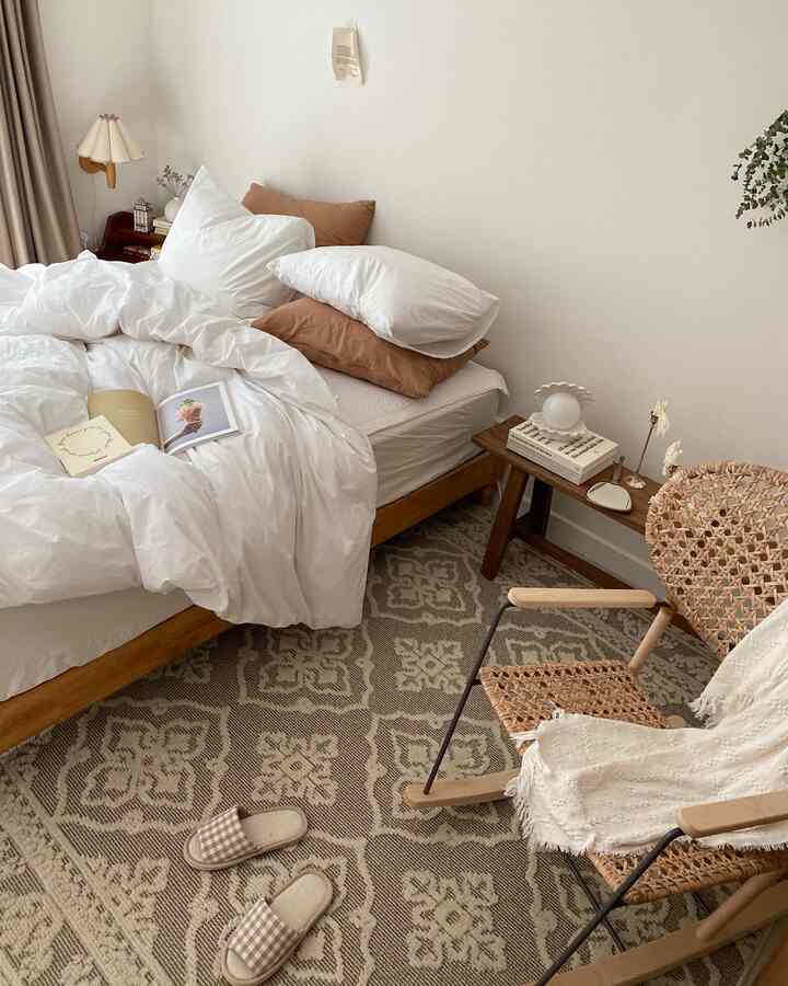 White and beige toned bedroom with wooden bed frame and patterned rug, a cozy natural modern style space